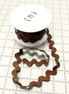 Brown ric rac on a white spool with a white background