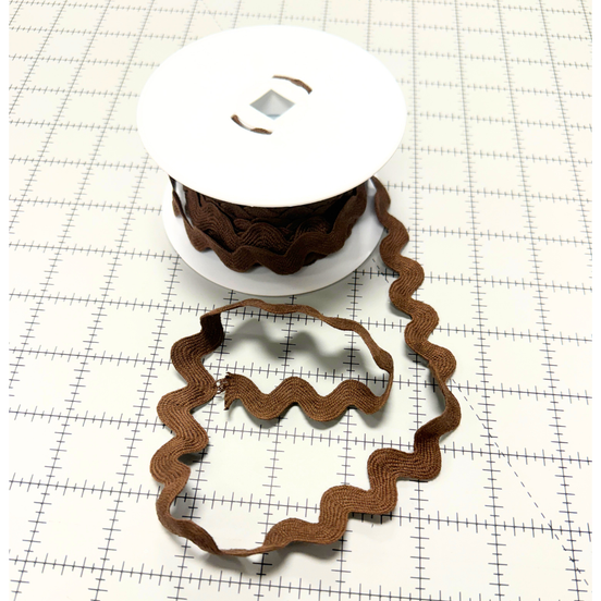 Brown ric rac on a white spool with a white background