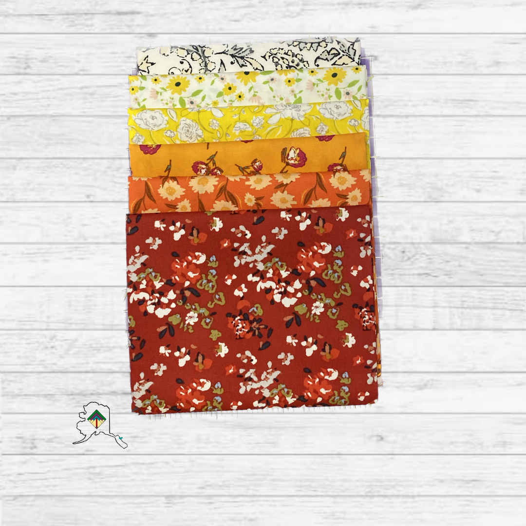 Stack of floral fabric panels in various colors on a wooden surface