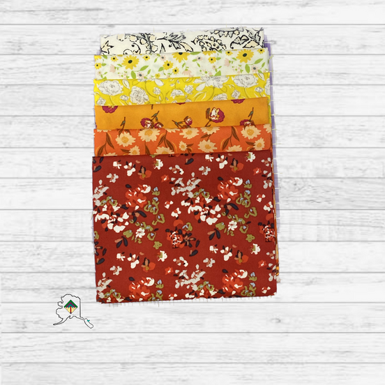 Stack of floral fabric panels in various colors on a wooden surface