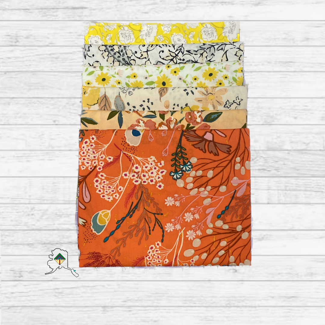 Stack of floral fabric swatches in various colors on a wooden surface