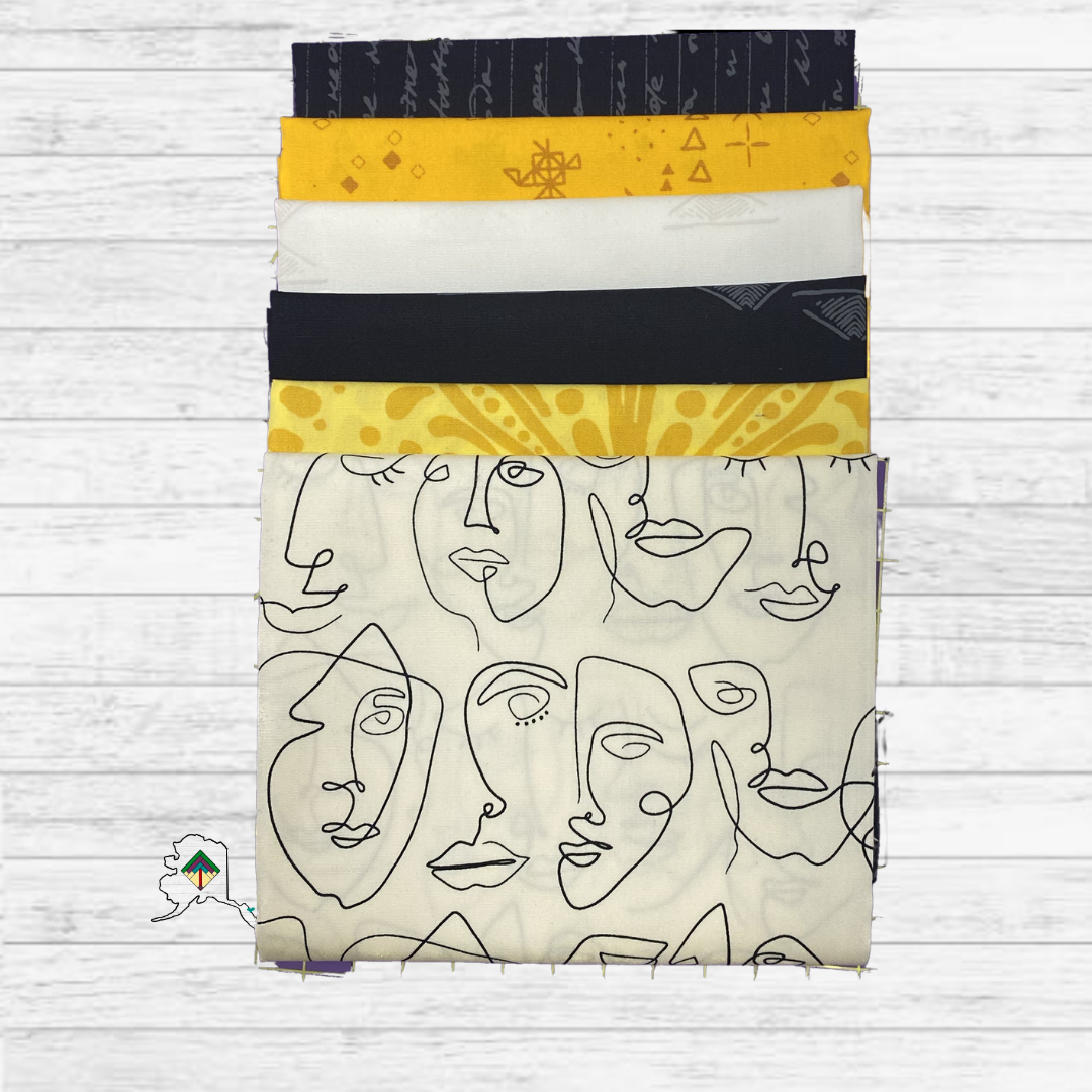 Stack of fabric panels with abstract face designs on a white wooden surface