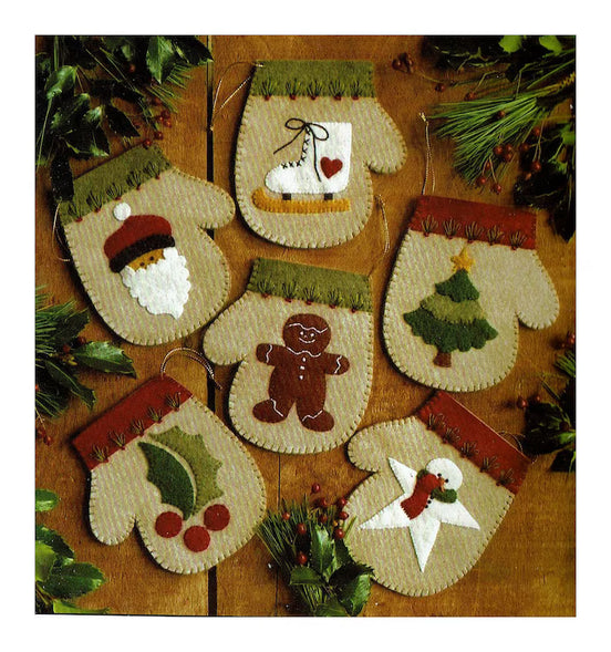 Set of felt Christmas ornaments shaped like mittens and snowmen on a wooden background.