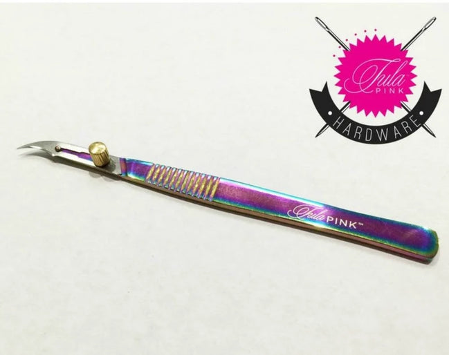 Multicolored craft knife with 'Tula Pink' branding on a white background