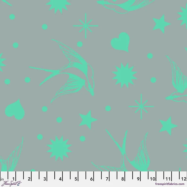 Fabric with aqua floral and star patterns on a gray background, featuring a ruler at the bottom.