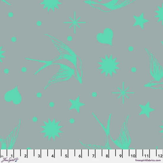 Fabric with aqua floral and star patterns on a gray background, featuring a ruler at the bottom.