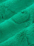 Close-up of teal textured fabric with pom-pom details