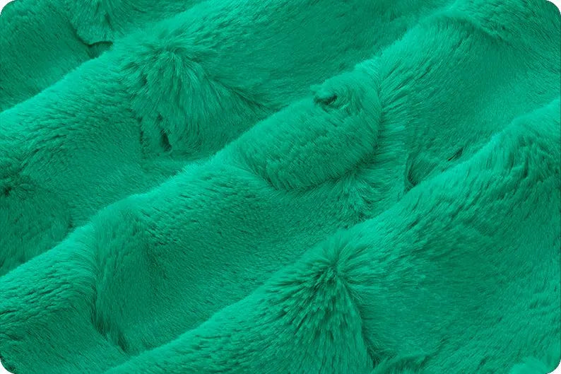 Close-up of teal textured fabric with pom-pom details