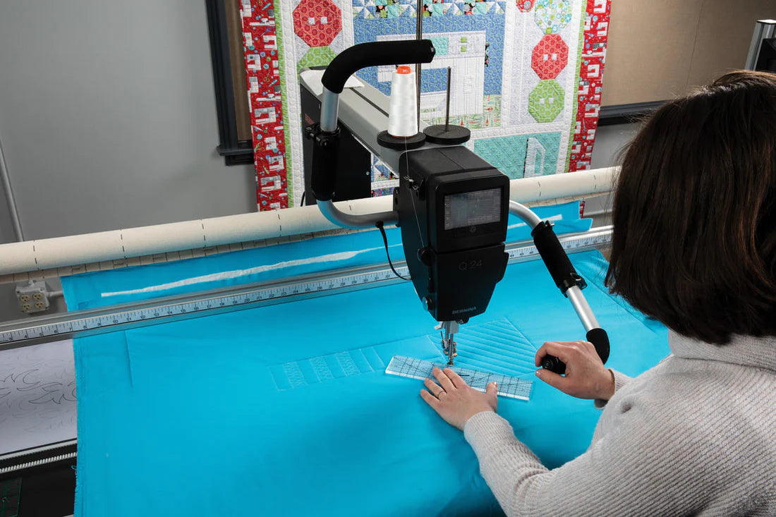 Person operating a quilting machine with a colorful quilt in the background
