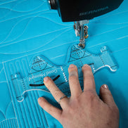 Sewing machine with a blue quilt and hand guiding a tool