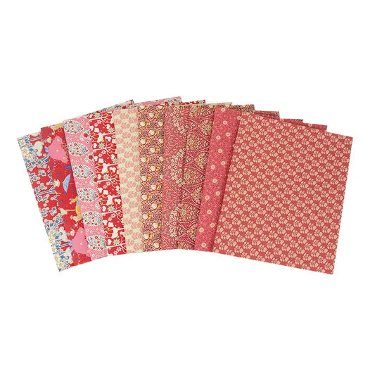Set of red and pink patterned fabric sheets on a white background